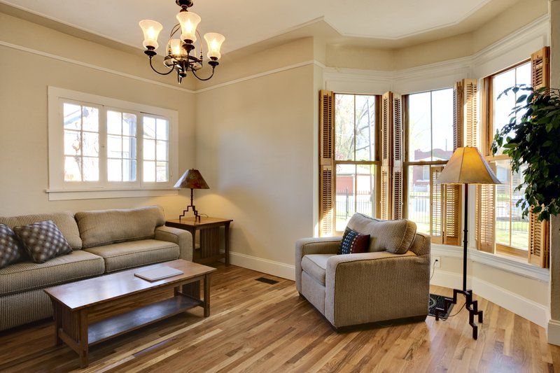 Bright living room with gray sofa, armchair, coffee table, and large sunlit windows