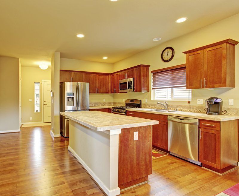 Bright modern kitchen with wood cabinets, stainless appliances, island, and hardwood floors