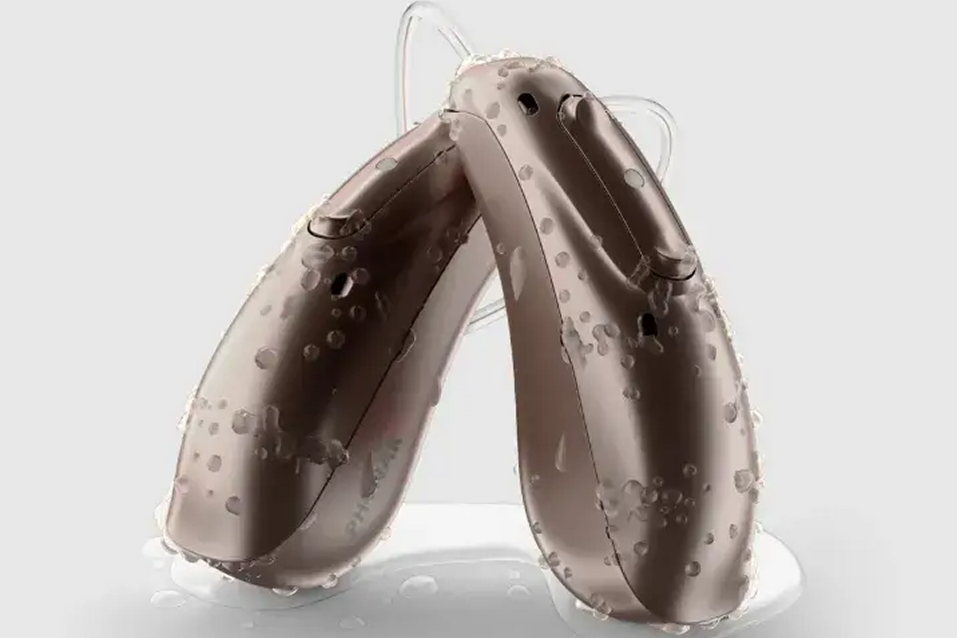 Two brown hearing aids with water droplets.