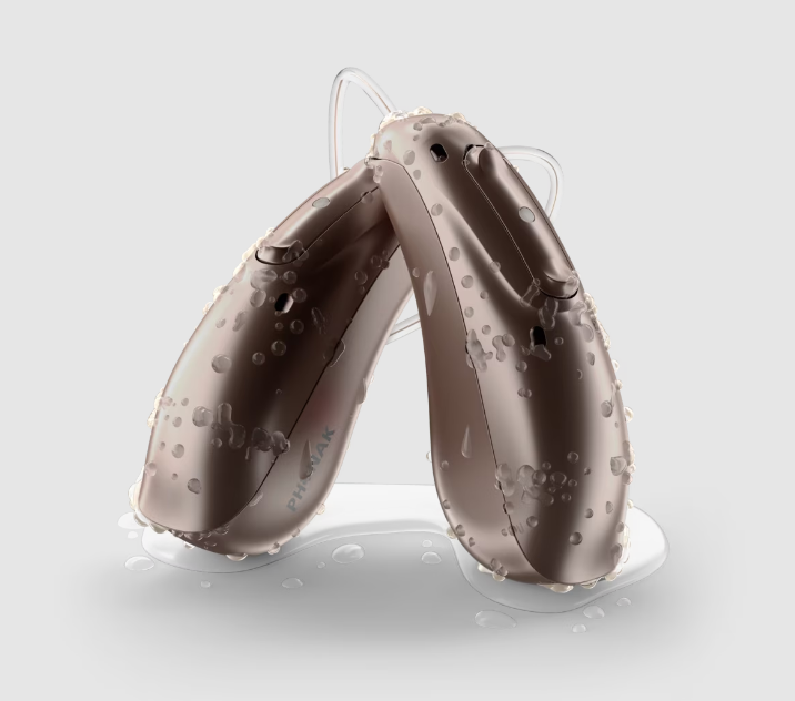 Two brown hearing aids with water droplets.