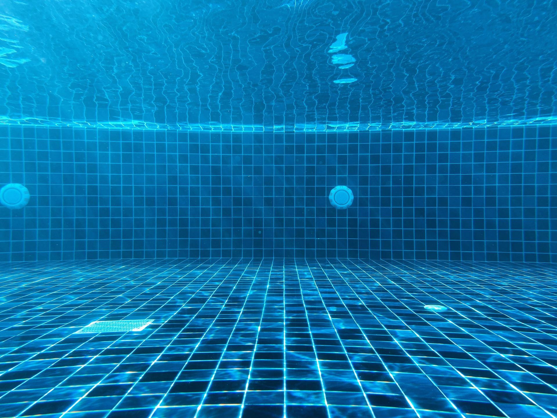 An underwater view of a swimming pool with blue tiles