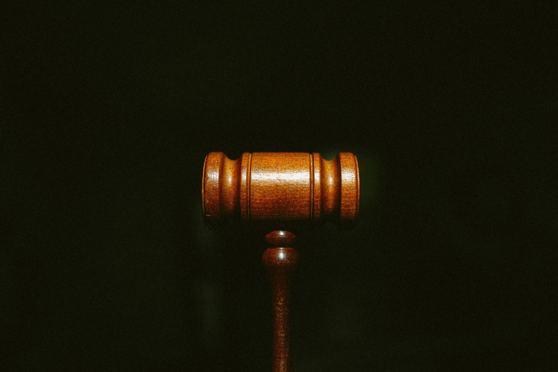 A close up of a wooden judge 's gavel on a black background.