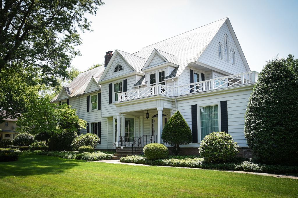 A large white house with a lush green lawn in front of it