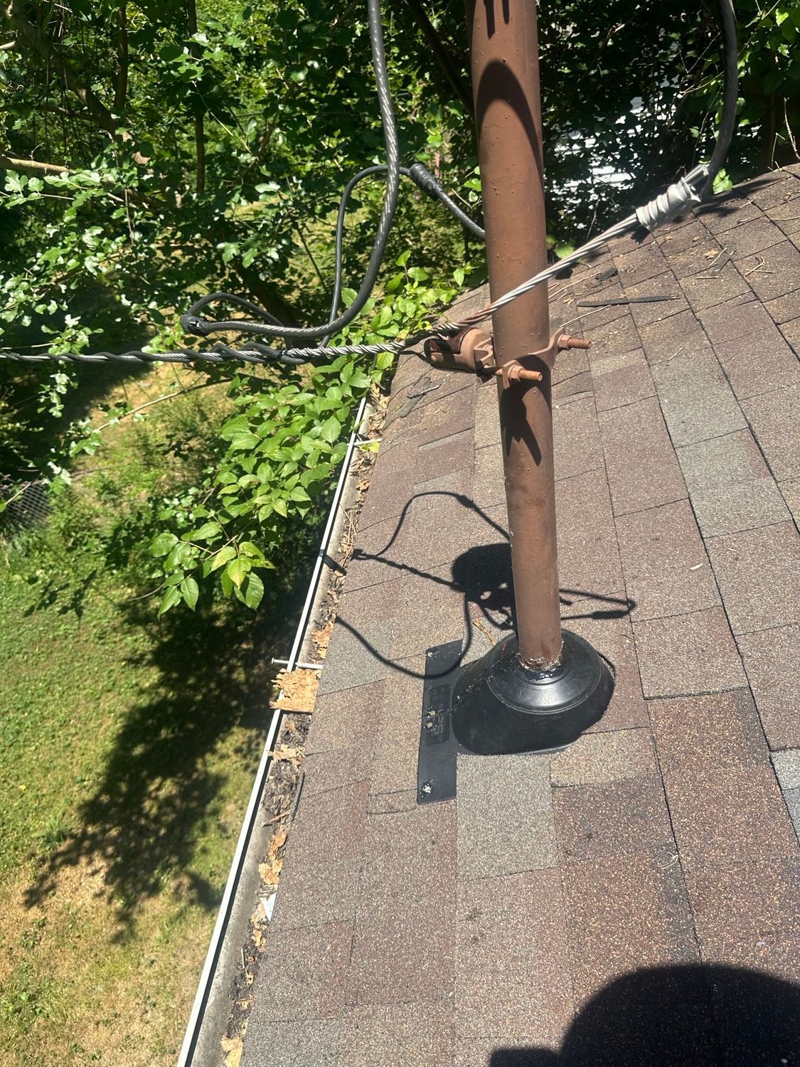 A pole with wires attached to it is sitting on top of a roof.