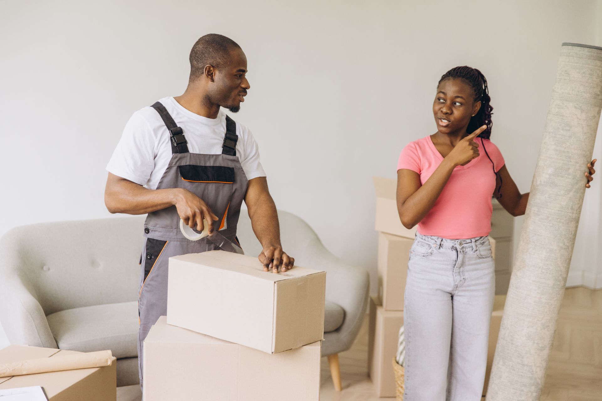 An African American mover packing next to a female African American client carrying a rolled carpet. An African American mover packing next to a female African American client carrying a rolled carpet.
