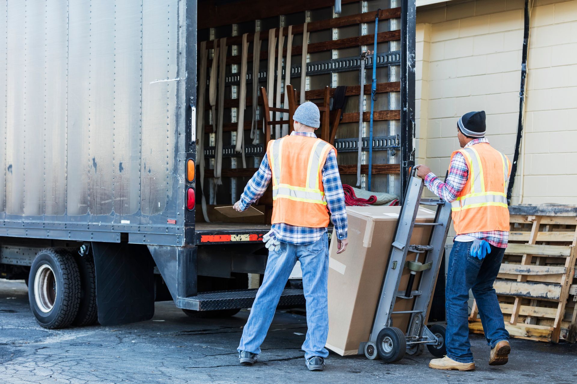 Two men in safety vests efficiently loading a truck, showcasing their role as commercial movers.