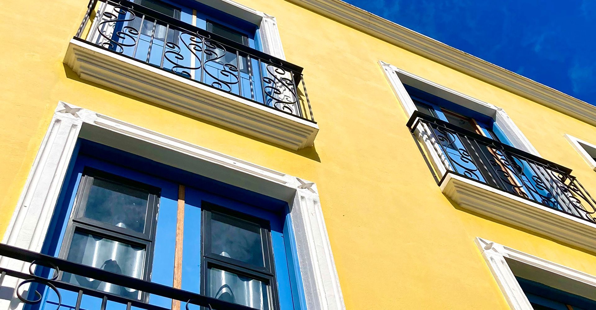 Um prédio amarelo com janelas e varandas azuis