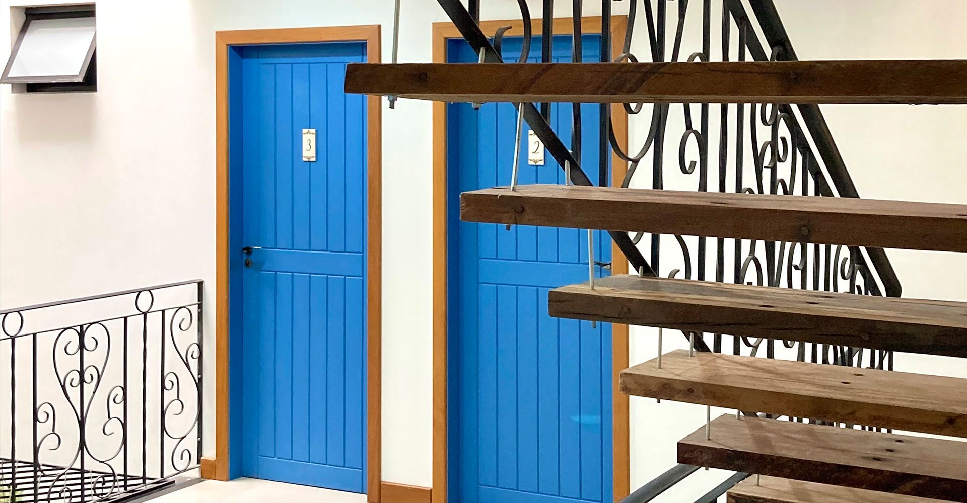 Um corredor com portas azuis e escadas de madeira