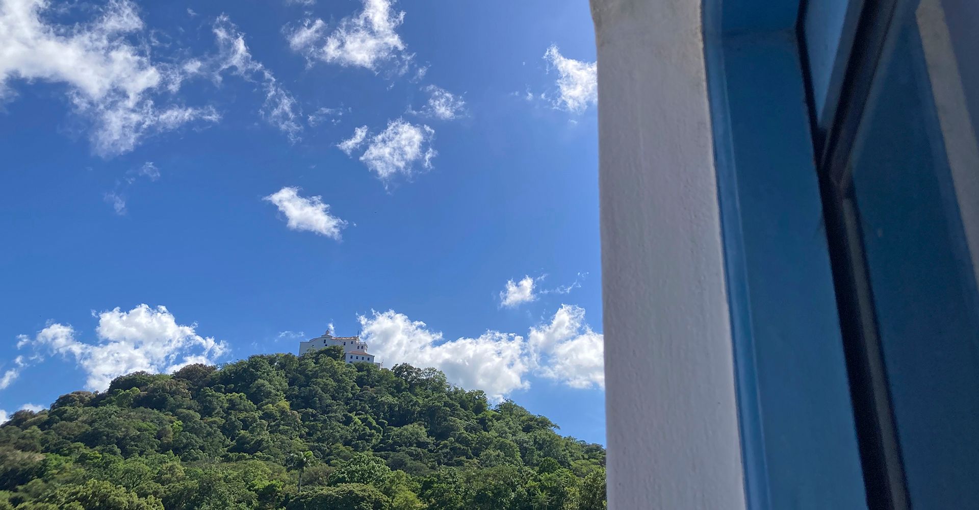 Uma vista de uma montanha de uma janela com céu azul e nuvens.