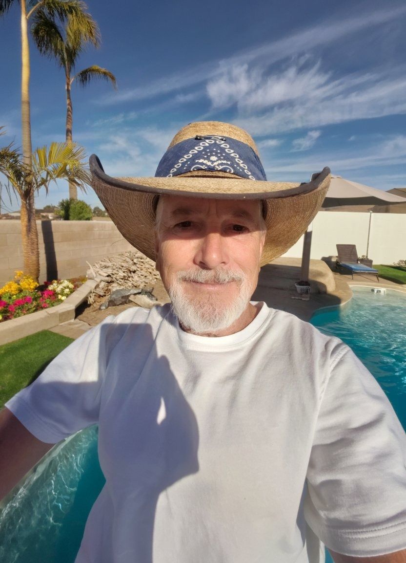 Man in a straw hat taking a selfie beside a swimming pool in a sunny backyard