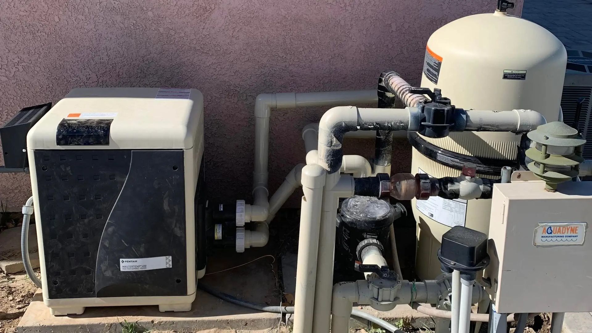 Outdoor pool equipment with pumps, pipes, and filters on a concrete pad