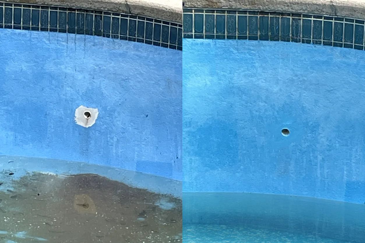 Empty blue swimming pool wall with a dark wet stain and two drain holes