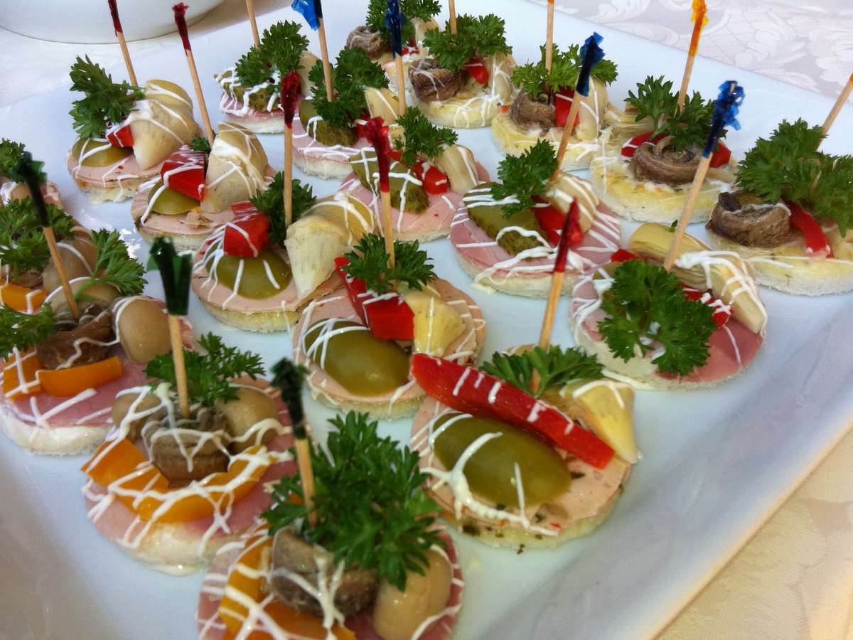 Un piatto bianco sormontato da una varietà di antipasti su stuzzicadenti
