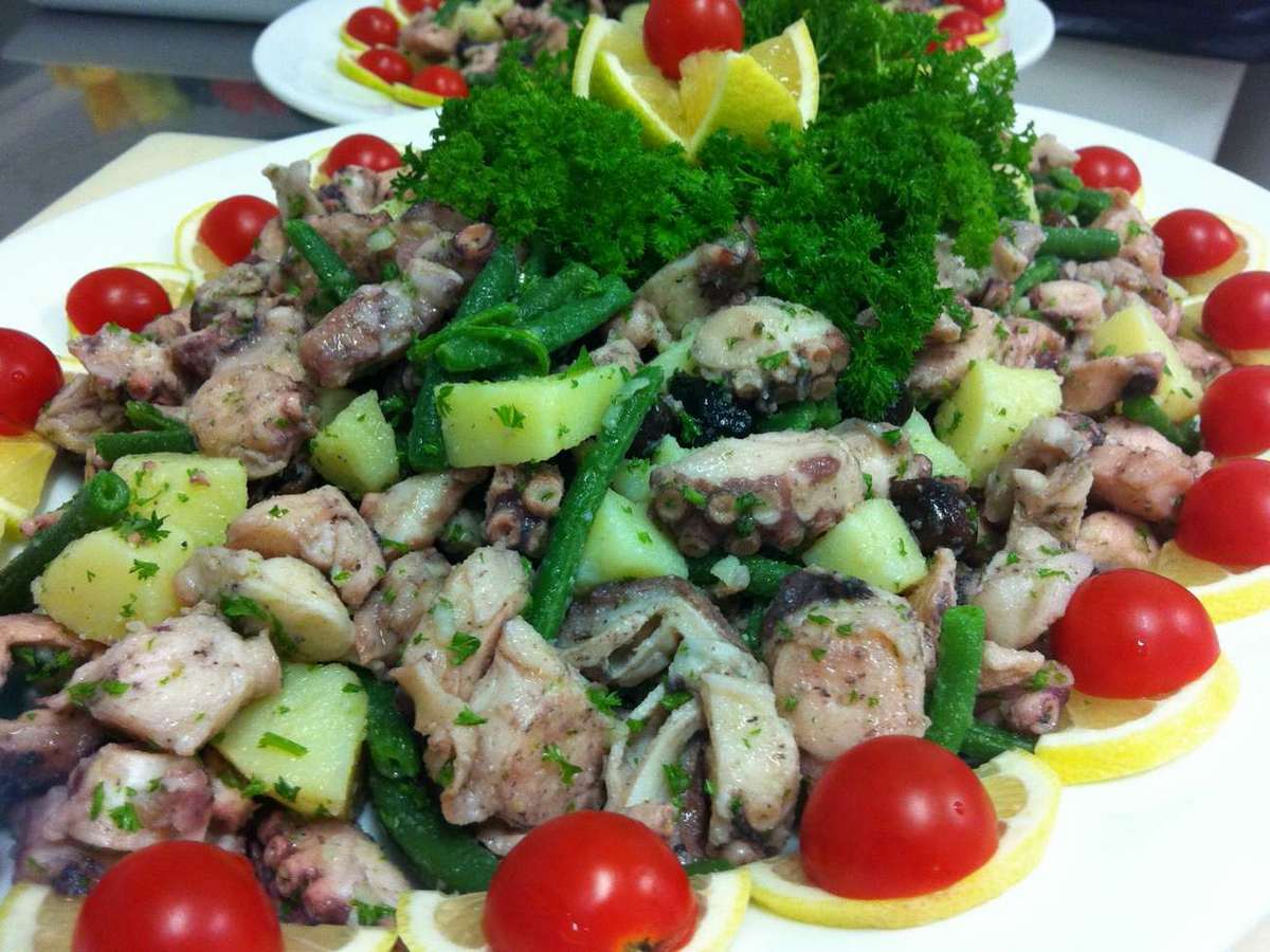 Un piatto di insalata di polpo con pomodori e fette di limone