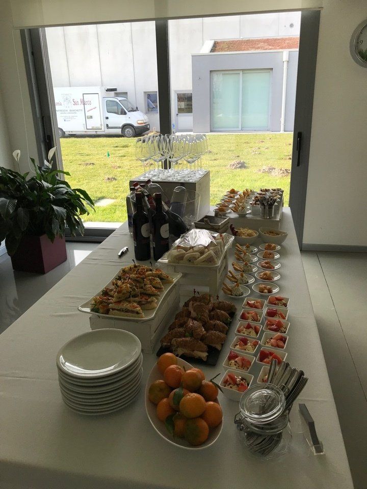 Un tavolo da buffet con piatti, ciotole di frutta e bicchieri di vino.
