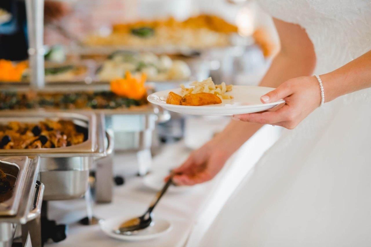 Una persona sta prendendo un piatto di cibo da un buffet.