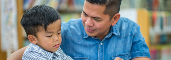 A father and his young son explore the materials and space of a Montessori classroom together.