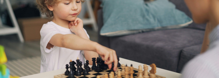 Principles of Gameschooling - A child playing Chess in the classroom. 
