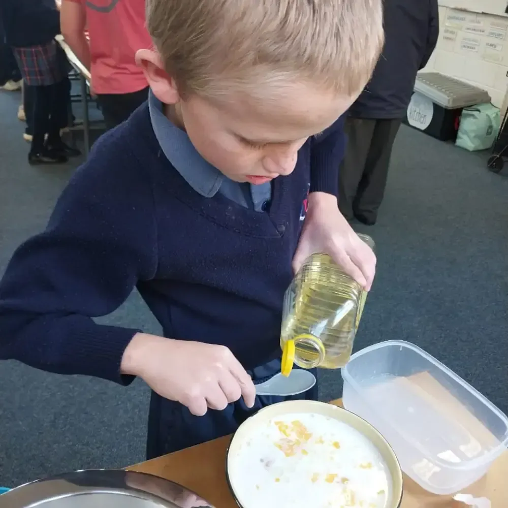 Child pouring liquid into a bowl during a classroom activity