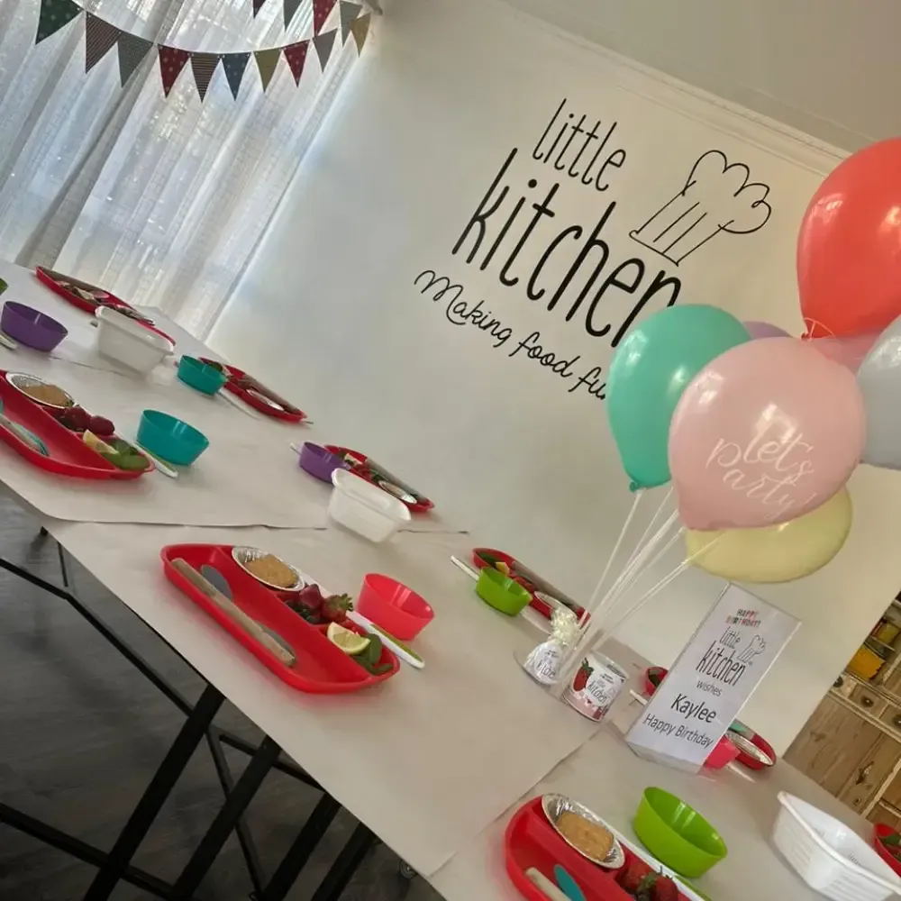 Decorated table at Little Kitchen bakery with colorful plates, balloons, and party favors for a celebration