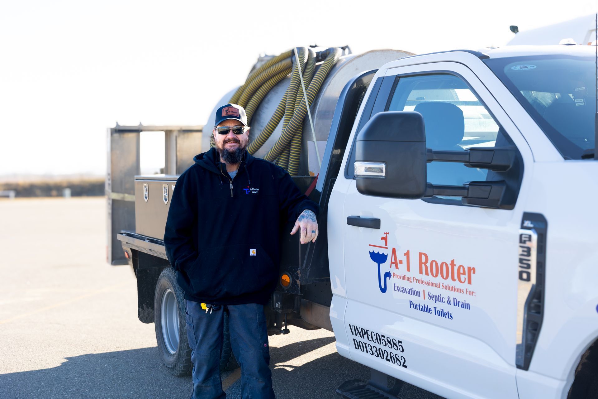 A man is standing next to a 1 rooter truck.