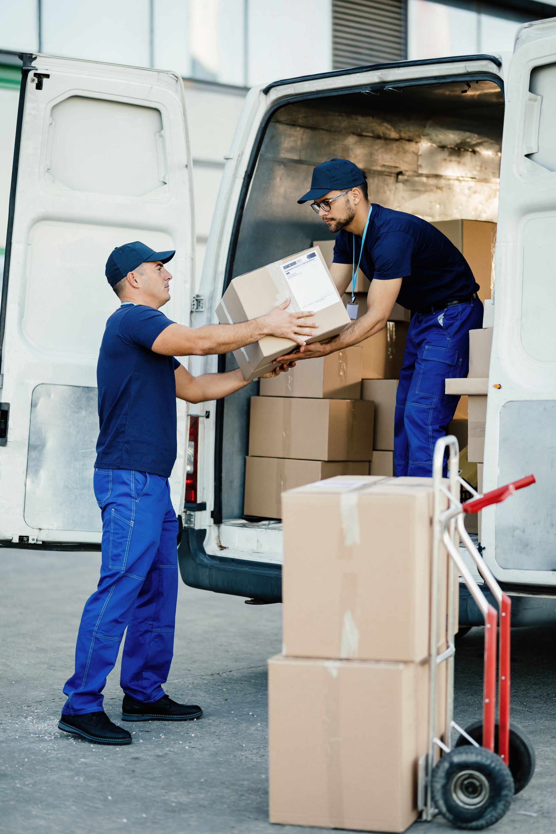two delivery men are loading boxes into a white van