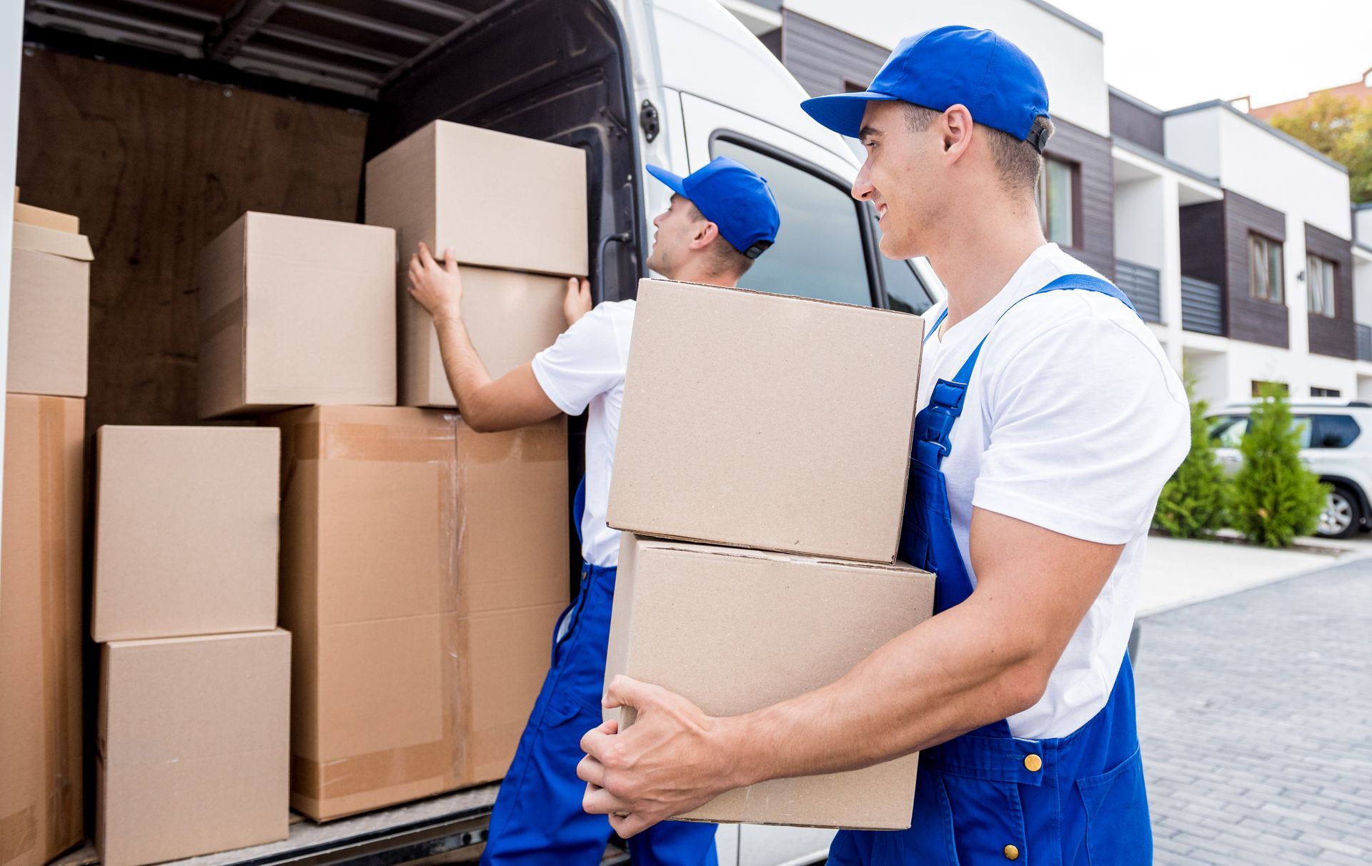 two men are carrying cardboard boxes out of a van