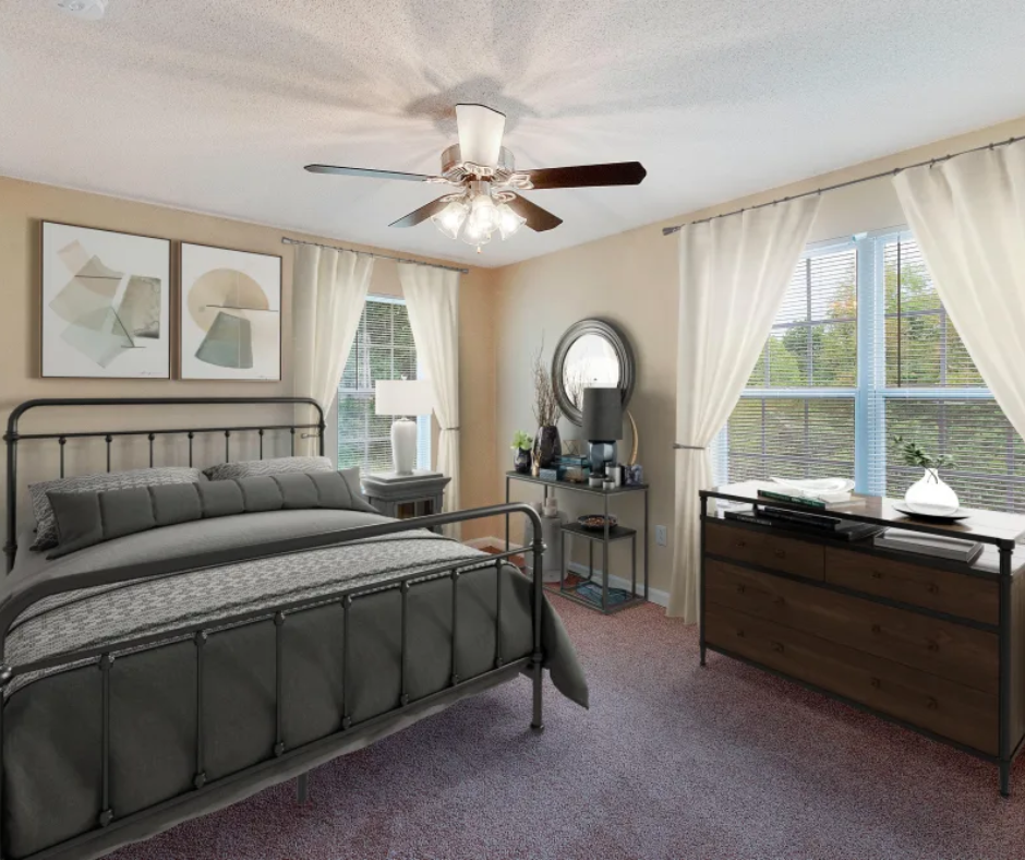 A cozy bedroom with a dark metal bed, neutral walls, carpet, a dresser, and a ceiling fan beside window curtains.