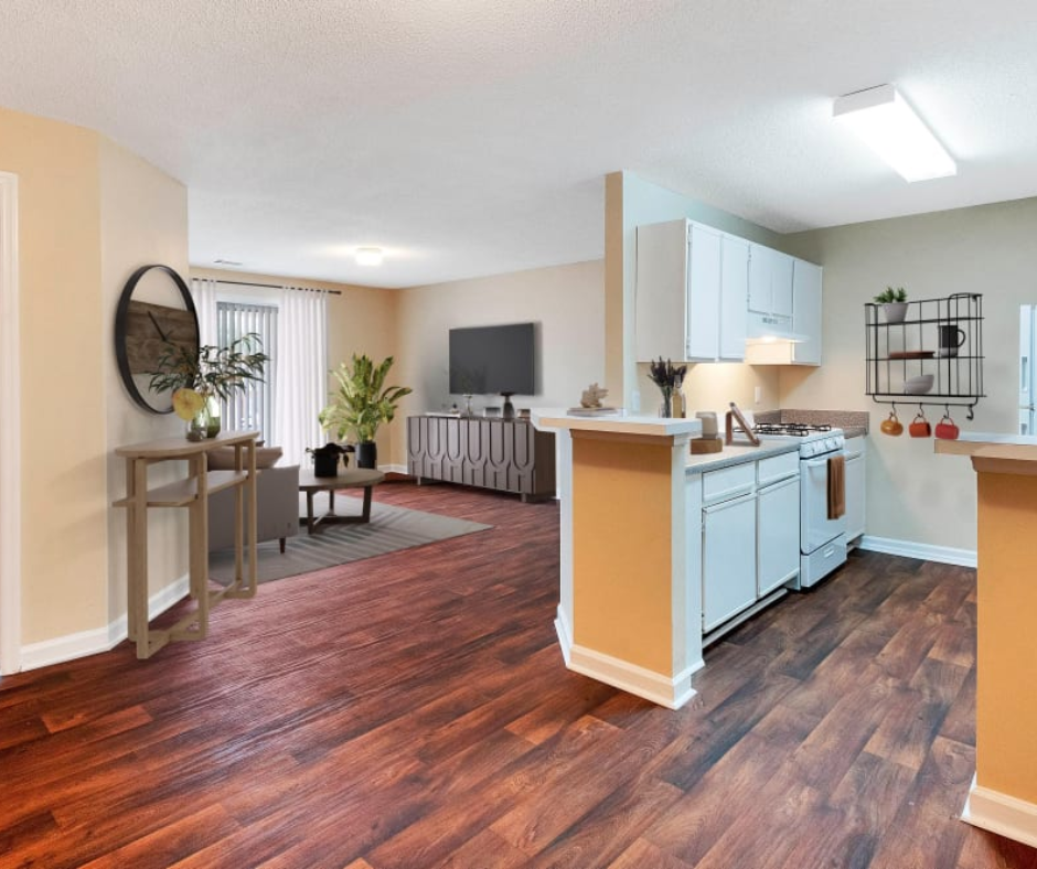 Open-plan apartment with dark wood floors, a modern kitchen, and a living area featuring a TV and a large round wall mirror.