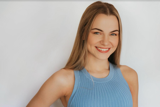 a woman in a blue tank top is smiling for the camera .