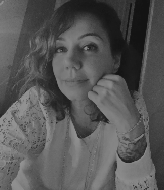 Woman in a patterned top, resting her chin on her hand, in a black-and-white selfie.