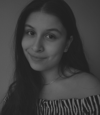 Young person with long dark hair, slight smile, wearing an off-shoulder zebra-print top.