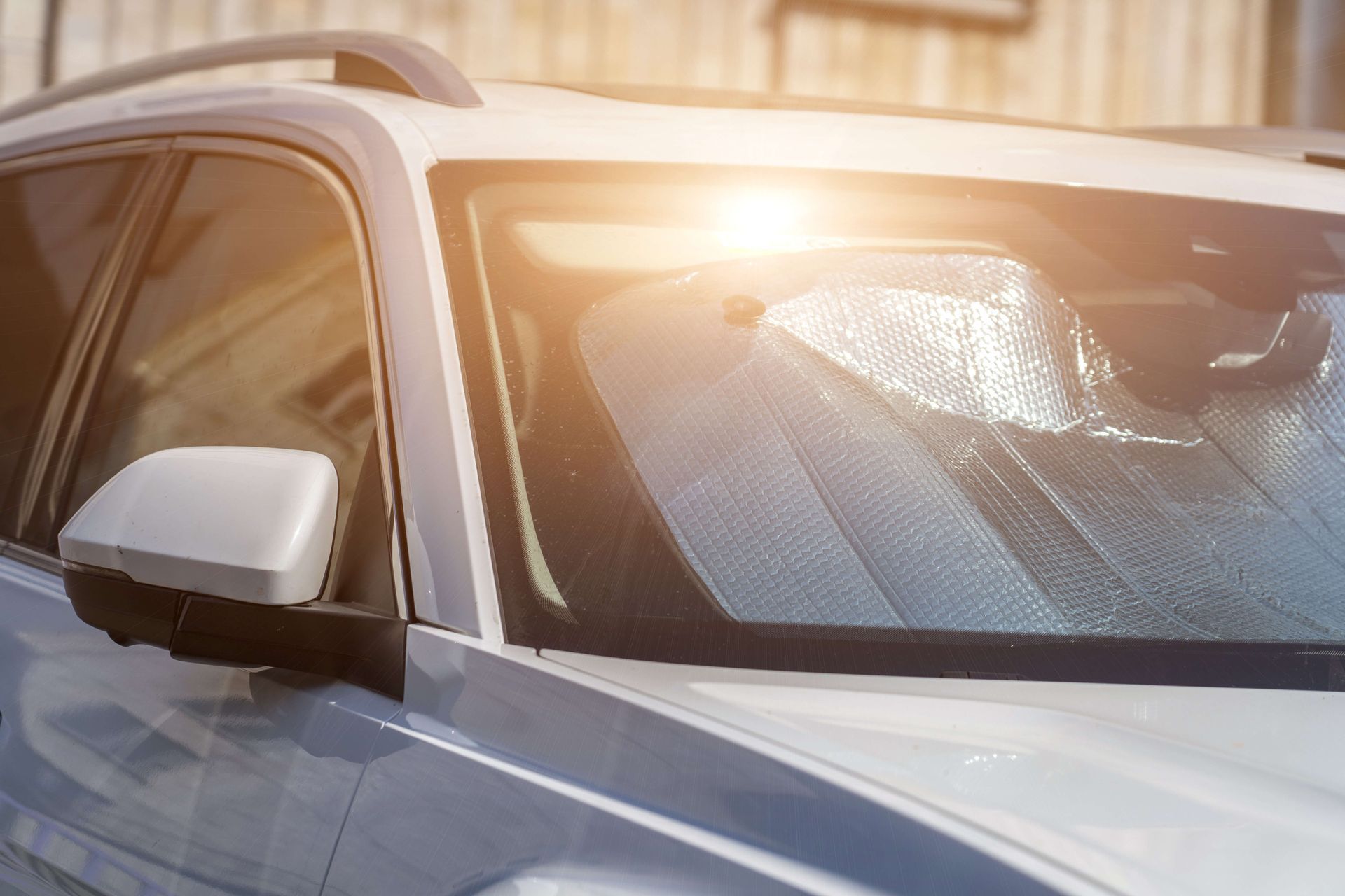 Silver SUV with frosted windshield and sunlight glare parked outdoors
