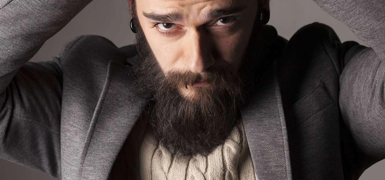 A man with a beard is wearing a hat and a jacket.