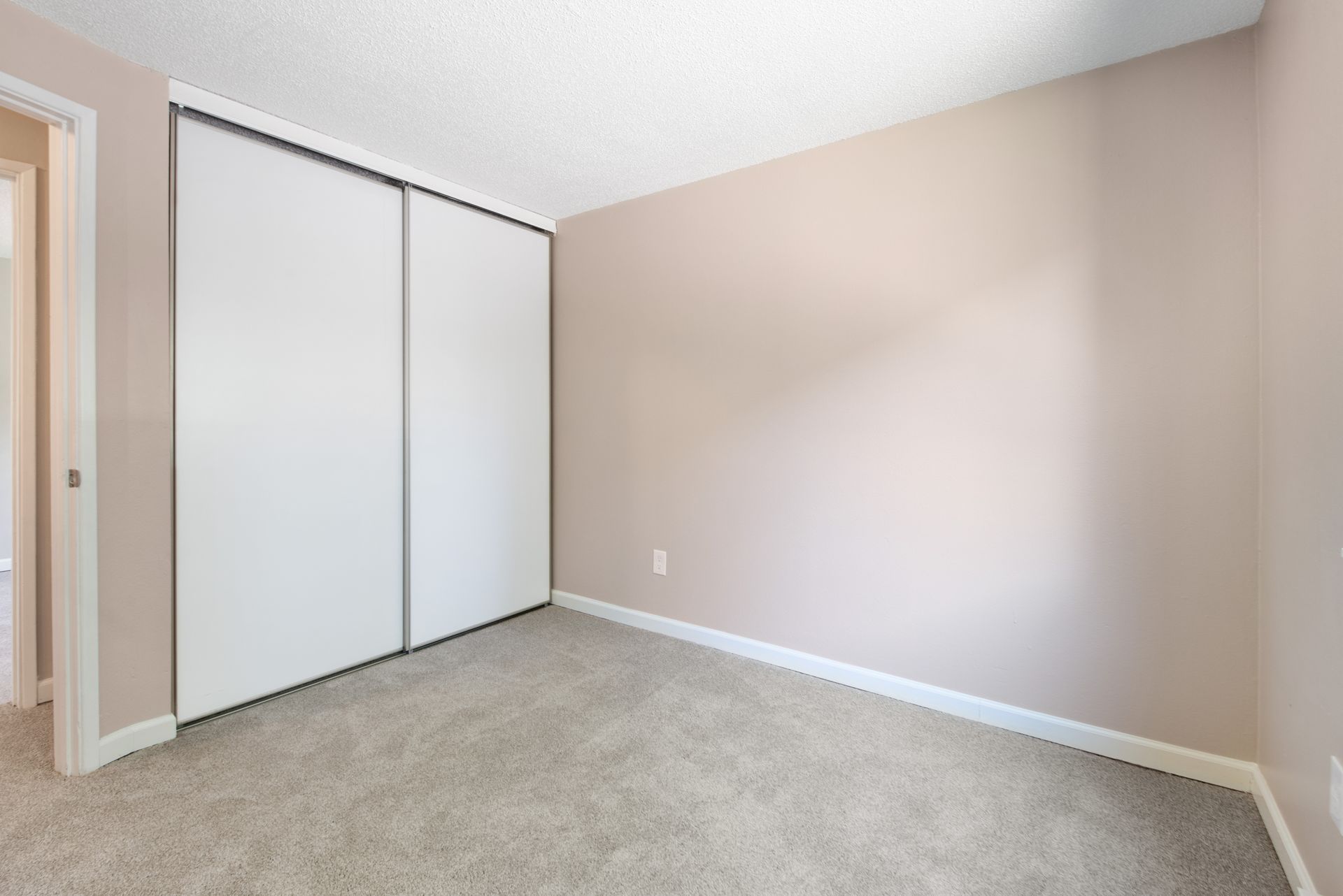Empty beige bedroom with carpet and sliding closet doors