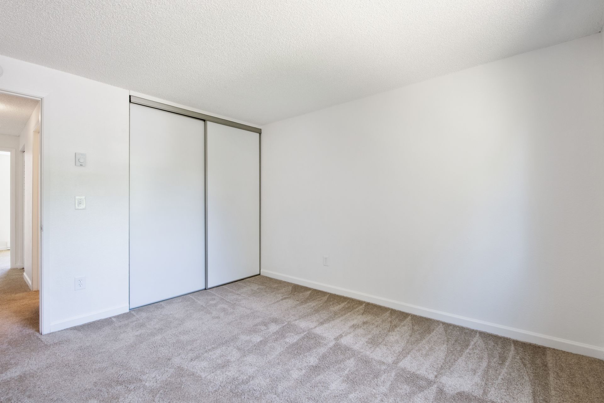 Empty white bedroom with carpet and sliding closet doors