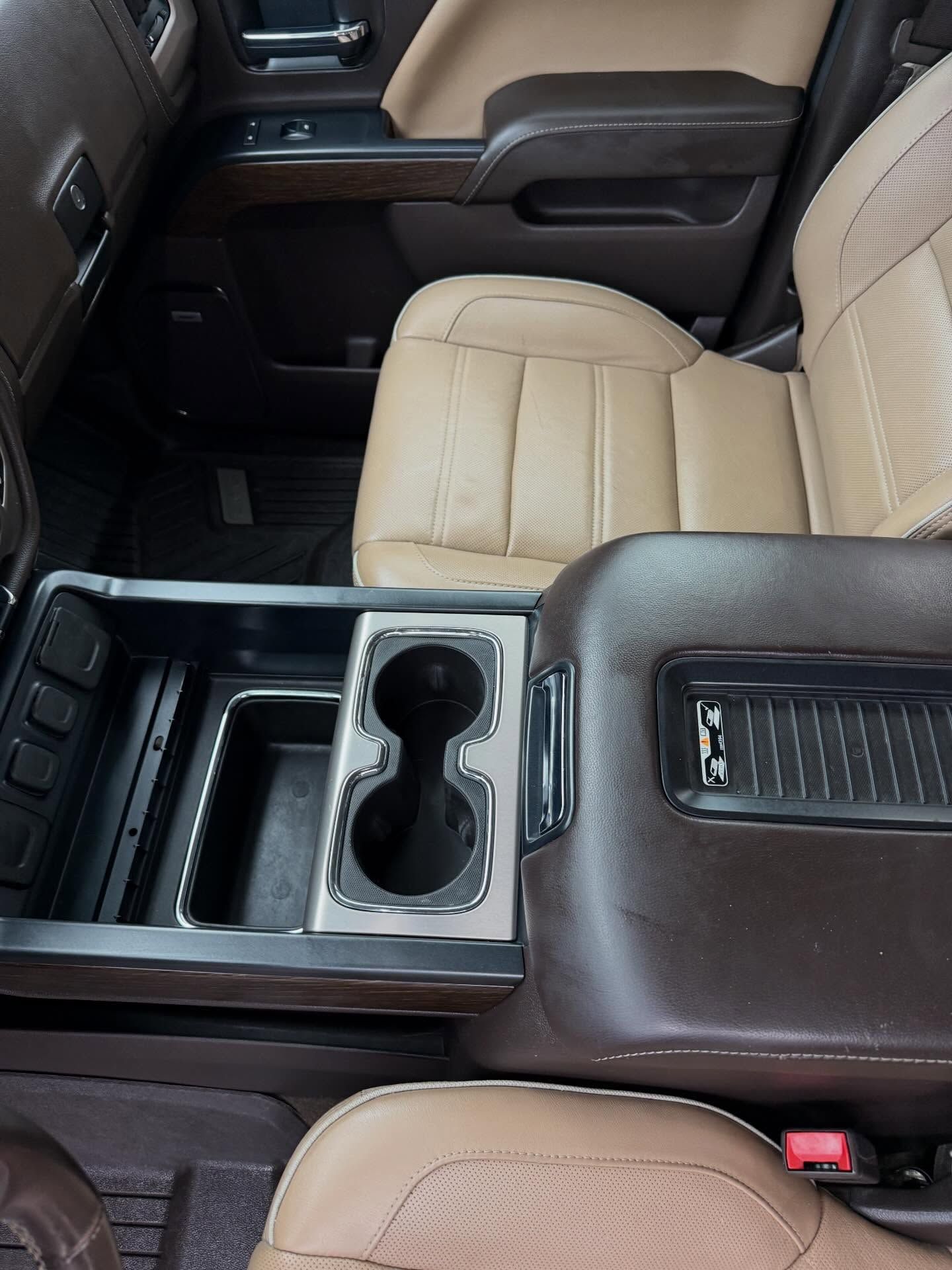 Car interior with beige leather seats and a center console holding cup holders and storage compartments