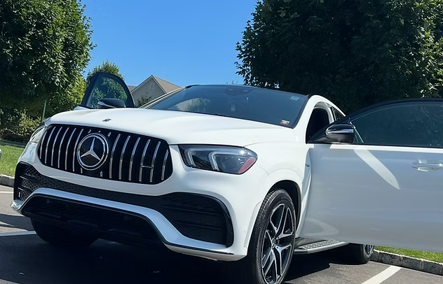 White Mercedes SUV with open door parked in a sunny lot, front view