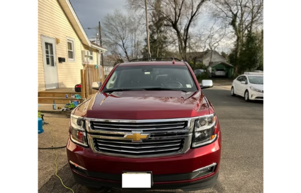 Maroon Chevrolet SUV parked in a driveway beside a house, viewed from the front.