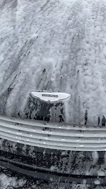 Snow-covered car hood and grille, with a Chrysler emblem visible beneath the frost.