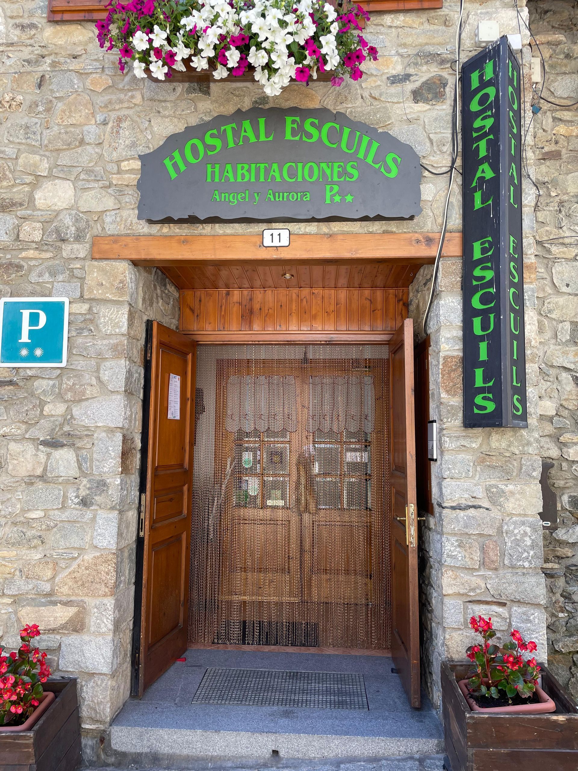 Un edificio de piedra con un cartel que dice hostal escuils