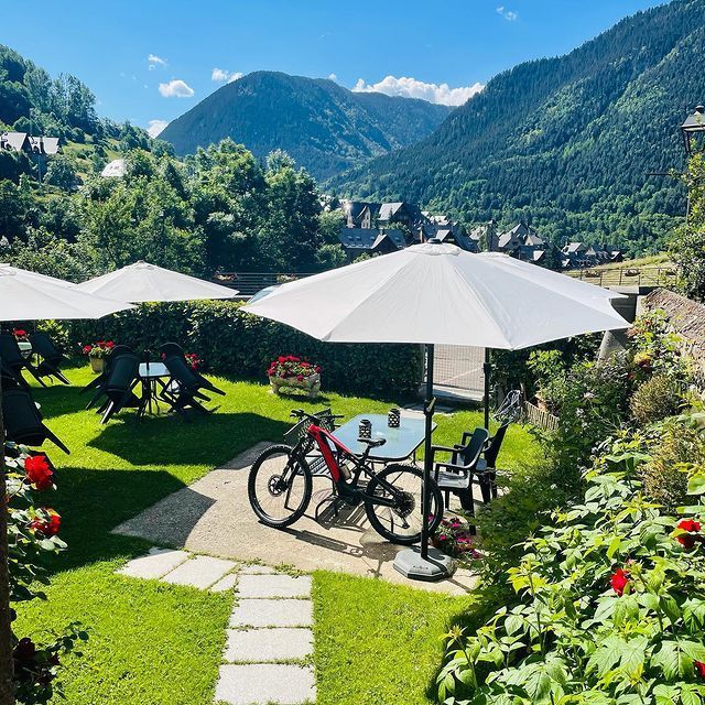 Una bicicleta está aparcada bajo una sombrilla en un jardín.