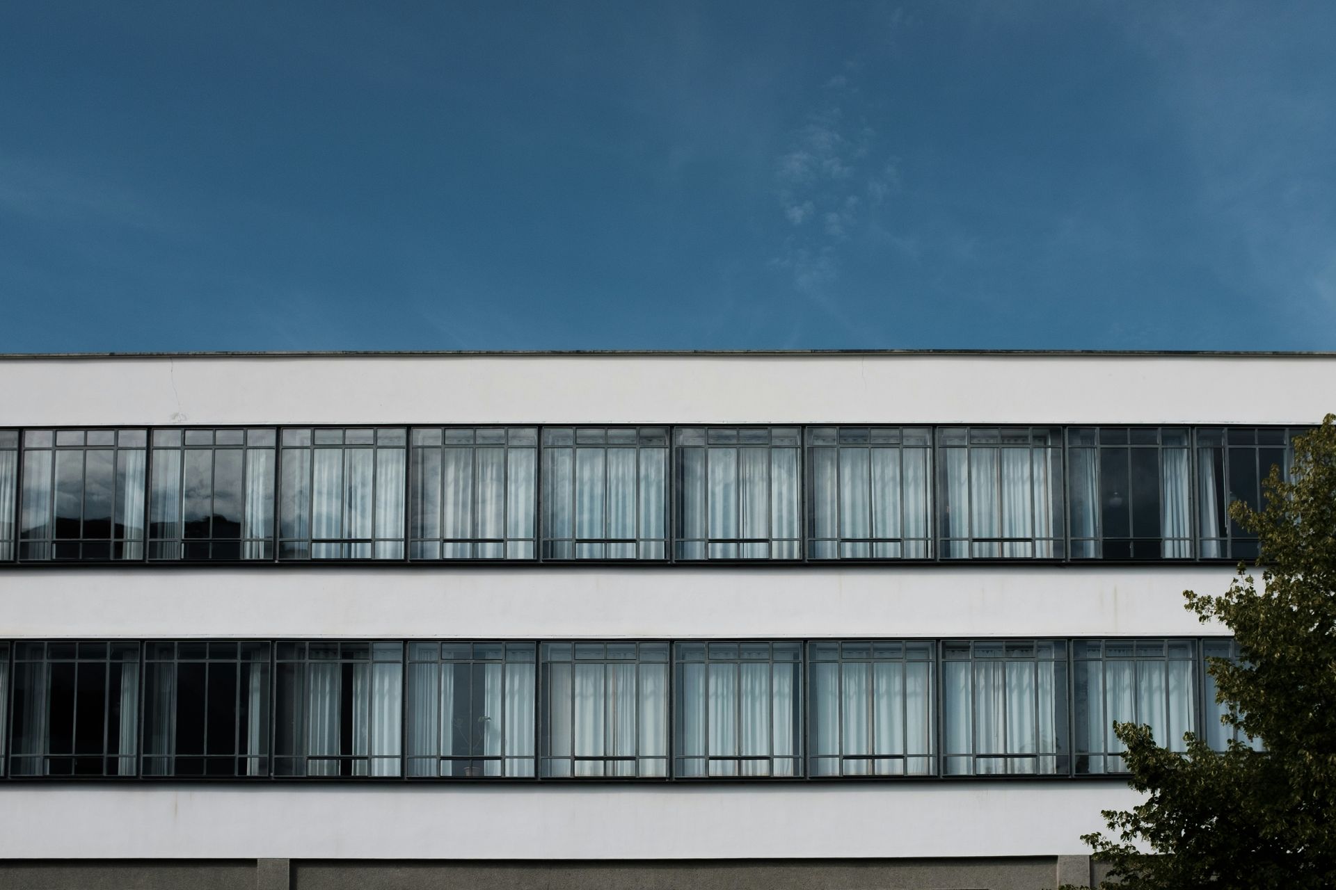 Modern building facade with long rows of windows beneath a blue sky