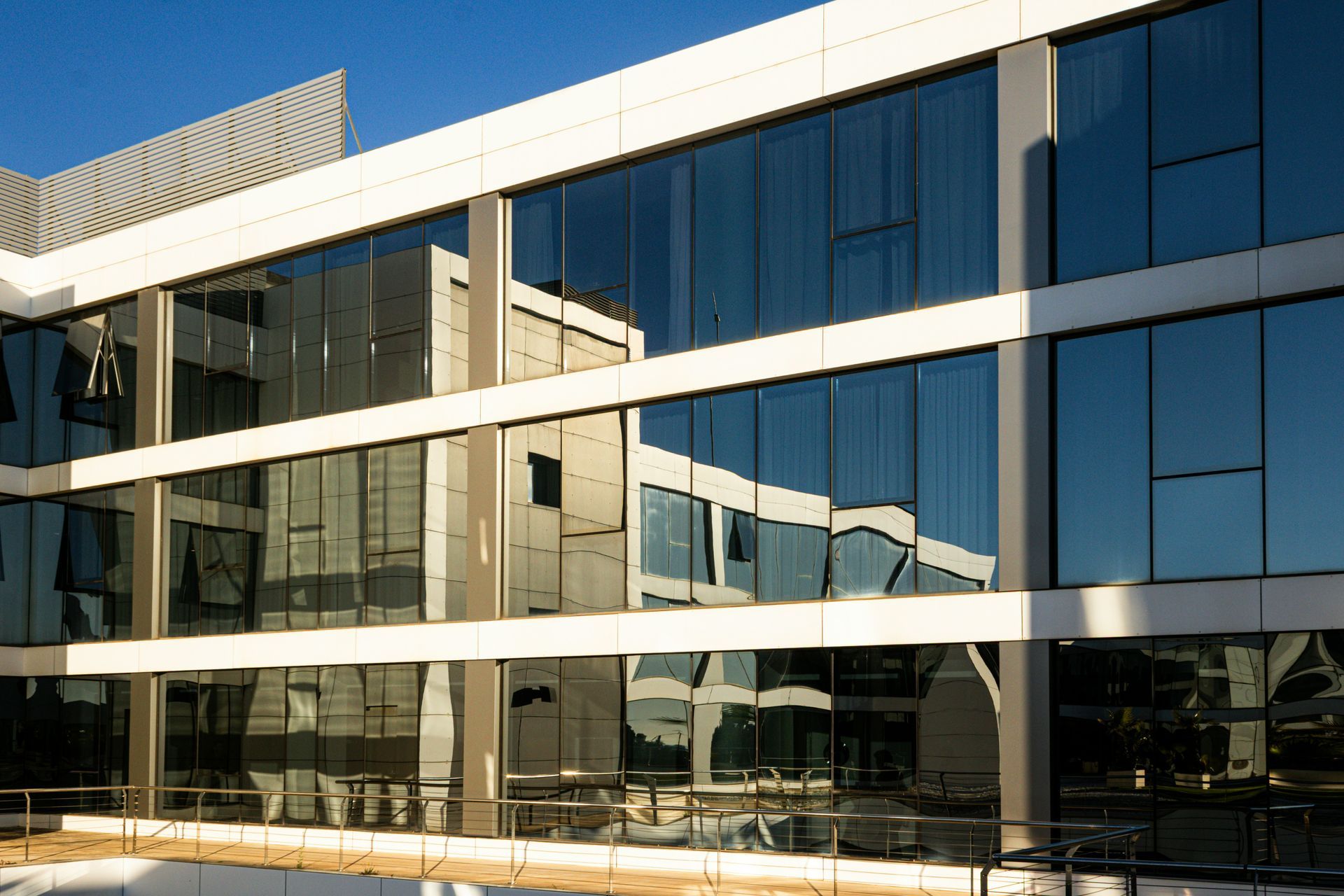 Modern glass office building with reflective windows and white horizontal beams