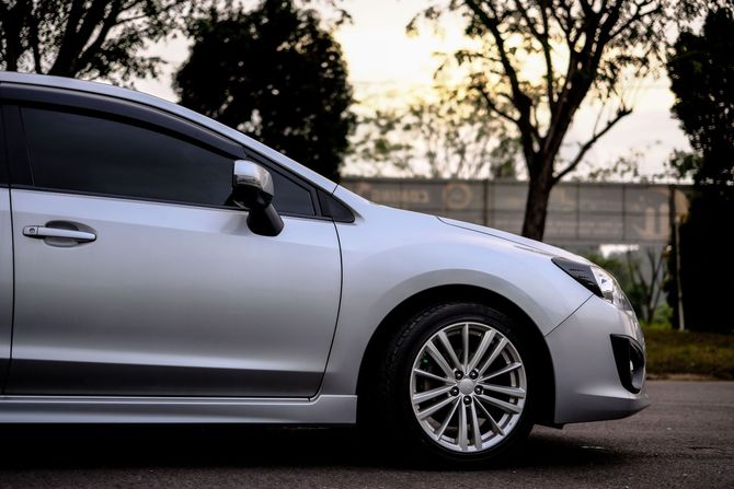Silver car parked outdoors at sunset, side view with trees in the background