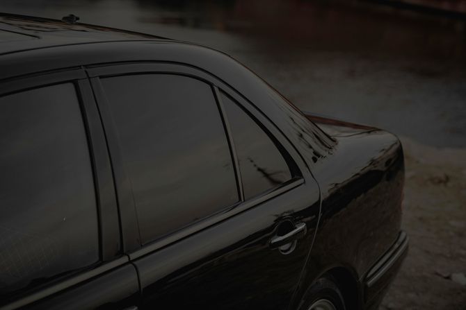 Dark sedan parked by a curb in rainy light