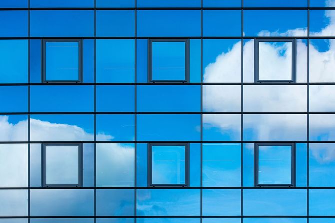 Blue glass building facade reflecting clouds and sky