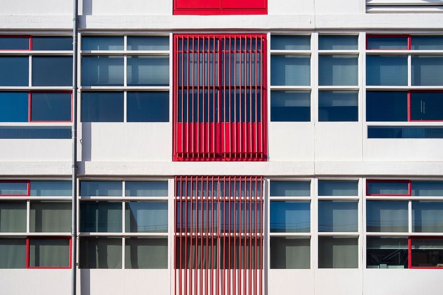 Modern building facade with red vertical accents and rows of windows