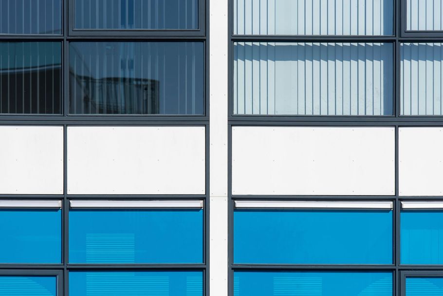 Modern building facade with blue and white windows and vertical blinds