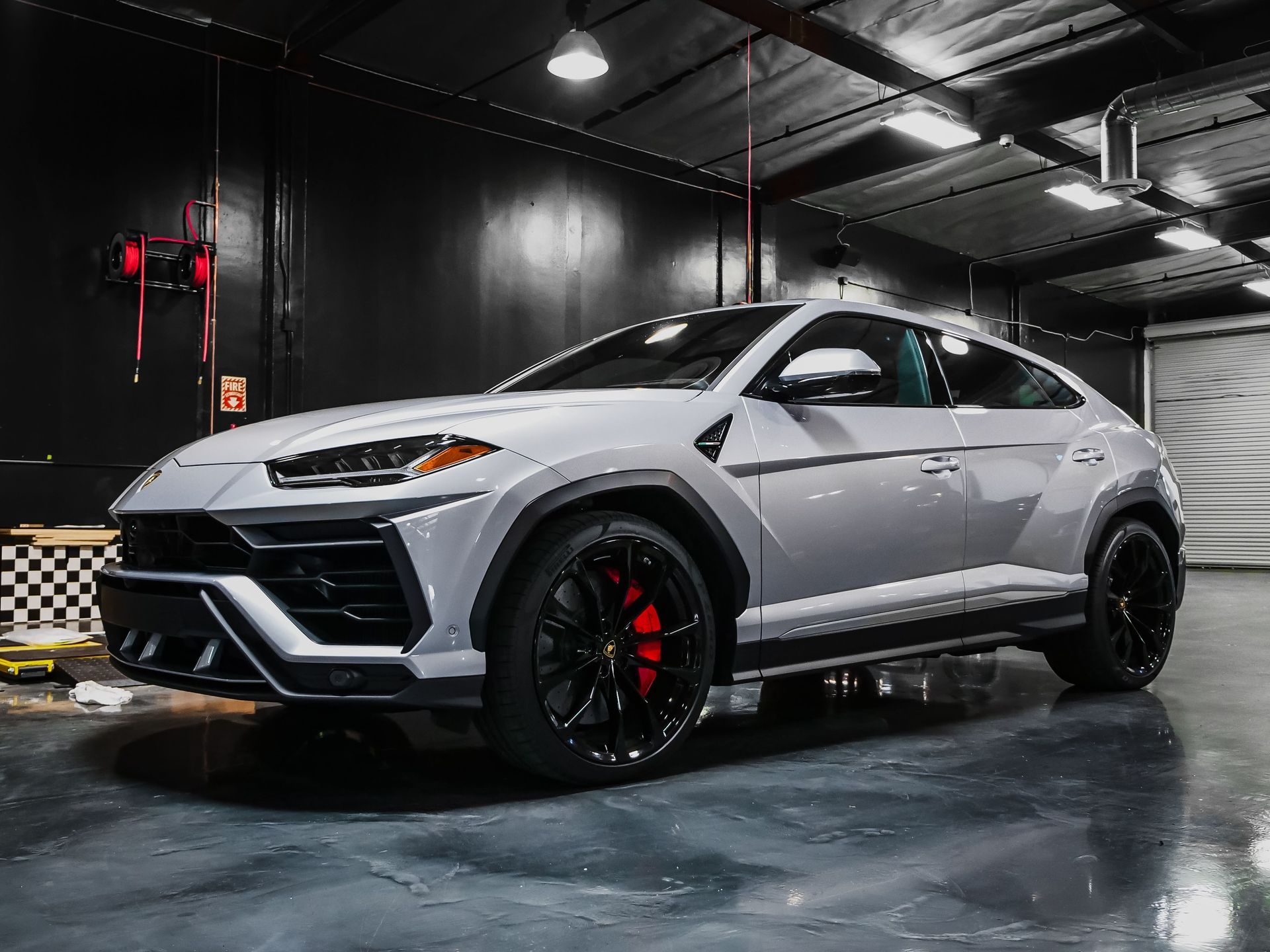 Silver sports SUV in a dark showroom, shown from the front-left with black rims and red brake calipers